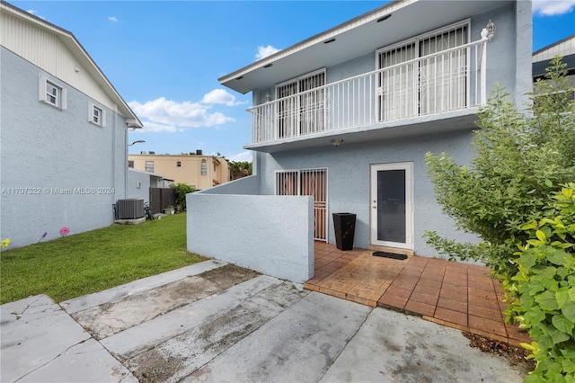 rear view of property featuring a patio, a lawn, and central air condition unit