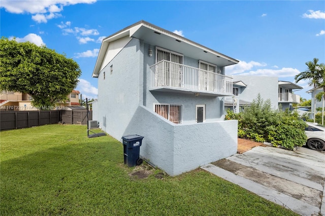 rear view of house with a balcony and a lawn