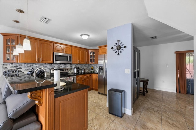 kitchen featuring stainless steel appliances, a kitchen breakfast bar, kitchen peninsula, decorative light fixtures, and decorative backsplash