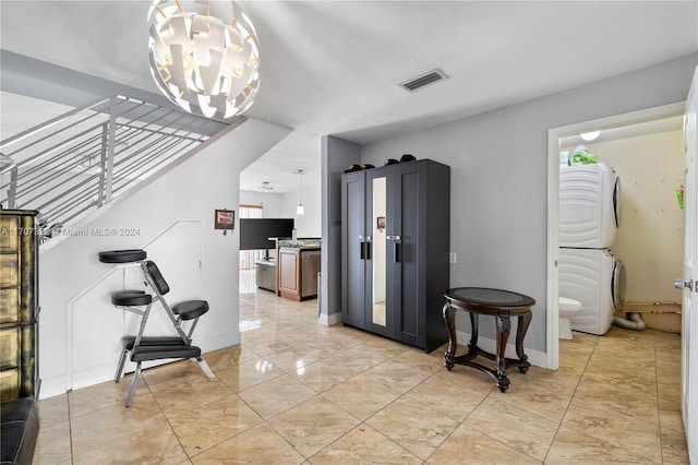 foyer entrance featuring stacked washer / drying machine and a notable chandelier