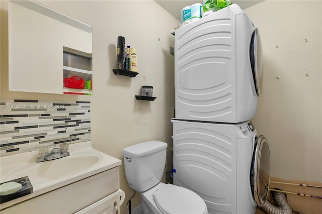 bathroom with backsplash, vanity, stacked washing maching and dryer, and toilet