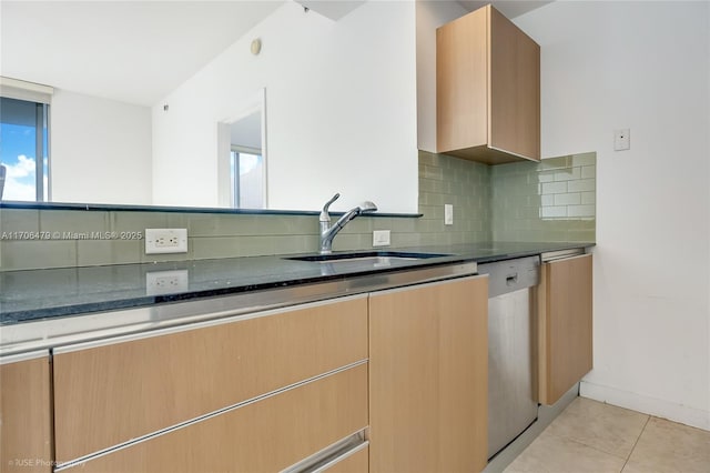 kitchen featuring tasteful backsplash, stainless steel dishwasher, sink, light tile patterned floors, and dark stone countertops