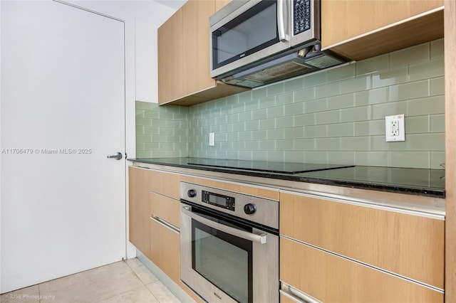 kitchen with tasteful backsplash, light tile patterned floors, and stainless steel appliances