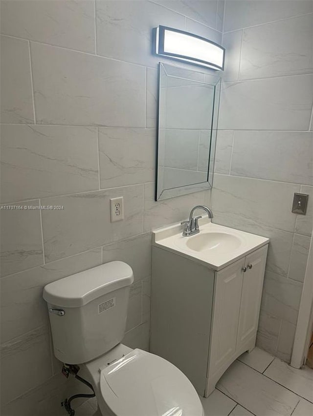 bathroom featuring vanity, toilet, and tile walls