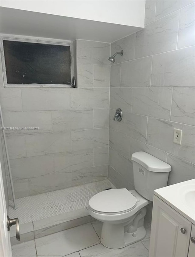 bathroom with a tile shower, vanity, and toilet