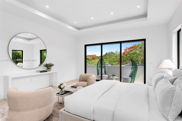 bedroom featuring access to exterior and a tray ceiling