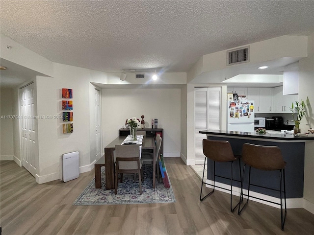 dining area with light hardwood / wood-style floors and a textured ceiling