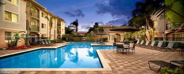 pool at dusk featuring a patio