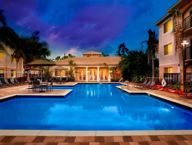 pool at dusk featuring a patio area