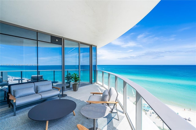 balcony featuring outdoor lounge area, a water view, and a beach view