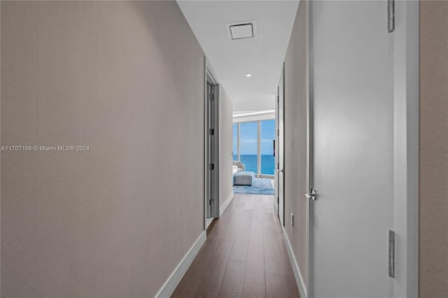 corridor with dark hardwood / wood-style flooring, floor to ceiling windows, and a water view