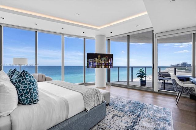 bedroom featuring hardwood / wood-style flooring, floor to ceiling windows, and a water view