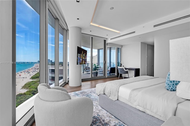 bedroom featuring multiple windows, a water view, dark wood-type flooring, and access to exterior