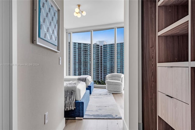 bedroom featuring an inviting chandelier, light hardwood / wood-style flooring, and a wall of windows