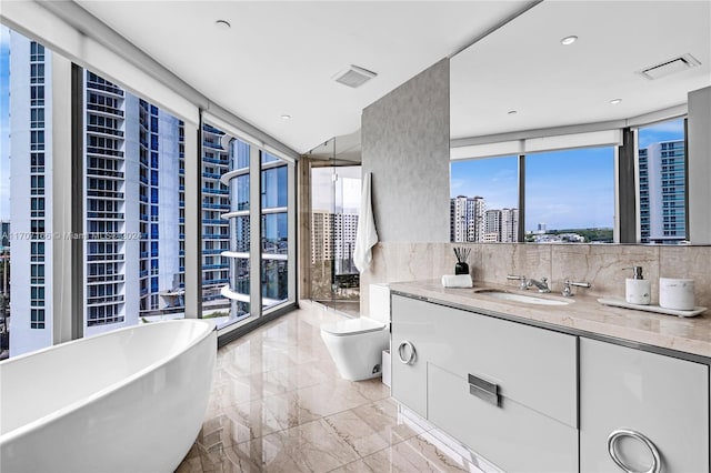 bathroom with vanity, a bathing tub, expansive windows, toilet, and tasteful backsplash