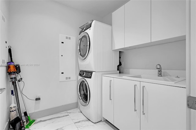 laundry area featuring cabinets, sink, and stacked washer and clothes dryer