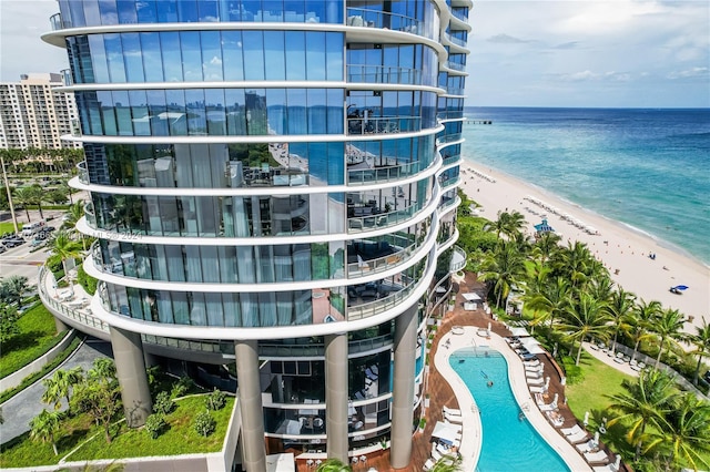 view of building exterior featuring a water view and a beach view