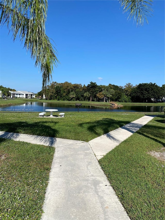 surrounding community with a water view and a yard