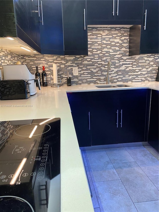 kitchen featuring decorative backsplash, blue cabinets, and sink