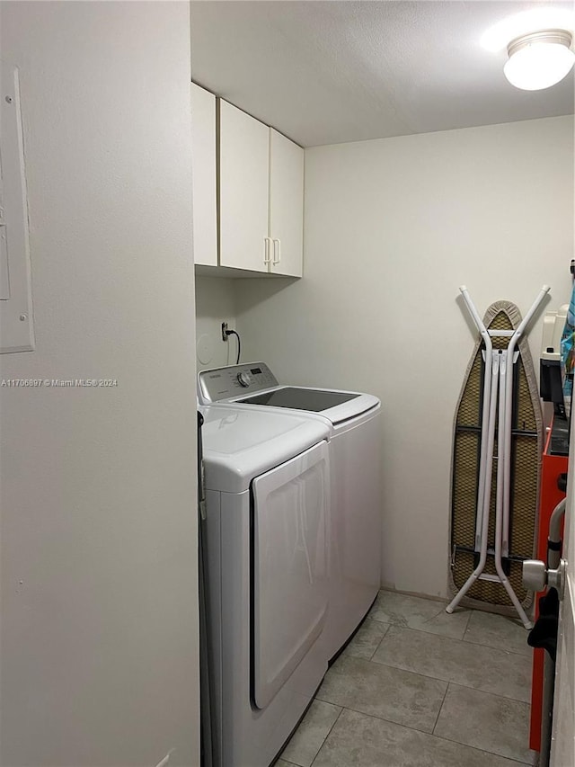 laundry room with washing machine and dryer, light tile patterned flooring, and cabinets