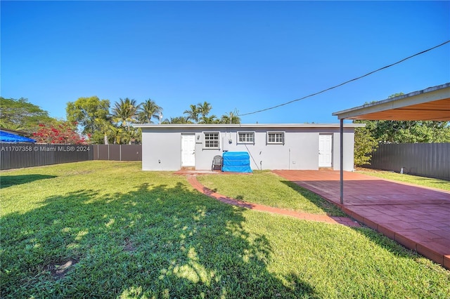 rear view of house featuring a lawn and a patio