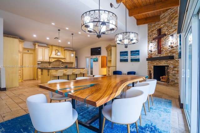 dining area featuring sink, an inviting chandelier, wooden ceiling, beamed ceiling, and a fireplace