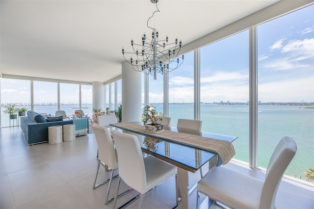 dining space featuring a notable chandelier, a water view, and a wall of windows