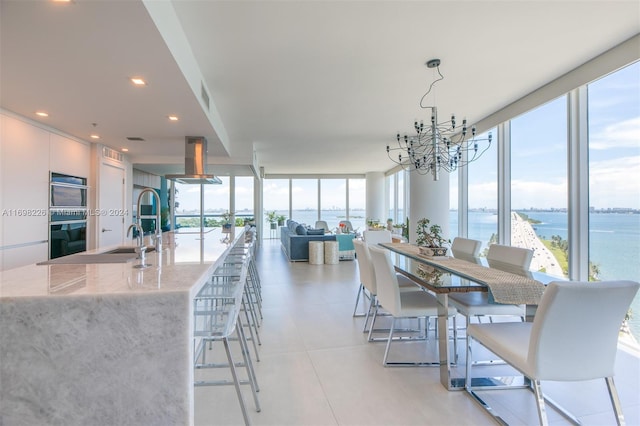 dining room with a chandelier, a water view, and expansive windows