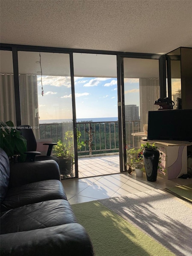 living room with tile patterned flooring, a textured ceiling, and a wall of windows