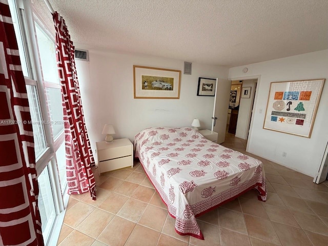 bedroom with multiple windows, light tile patterned flooring, and a textured ceiling