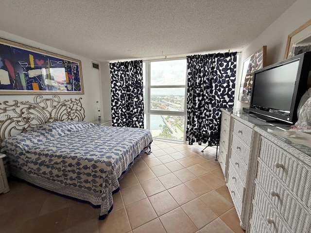 tiled bedroom featuring a textured ceiling and a wall of windows