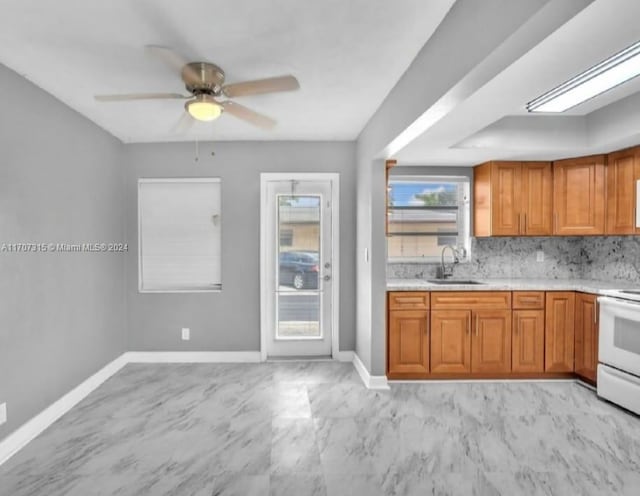 kitchen with tasteful backsplash, ceiling fan, sink, and white stove