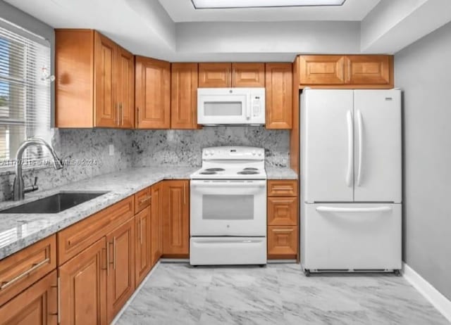 kitchen featuring light stone countertops, white appliances, tasteful backsplash, and sink