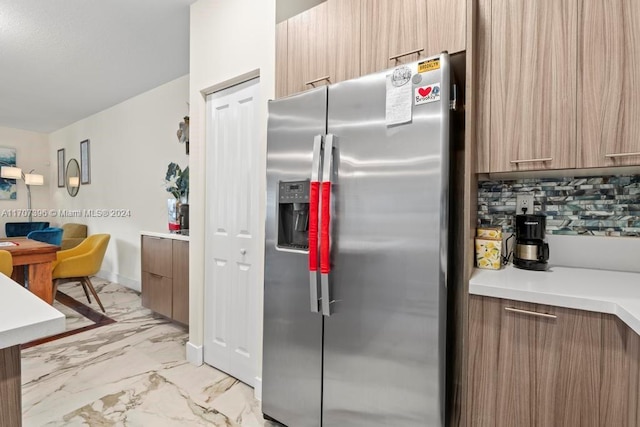 kitchen with stainless steel fridge with ice dispenser and tasteful backsplash