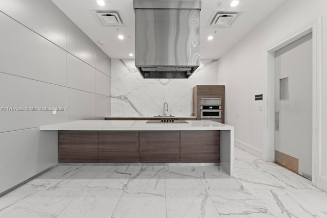 interior space featuring kitchen peninsula, stainless steel oven, range hood, and sink