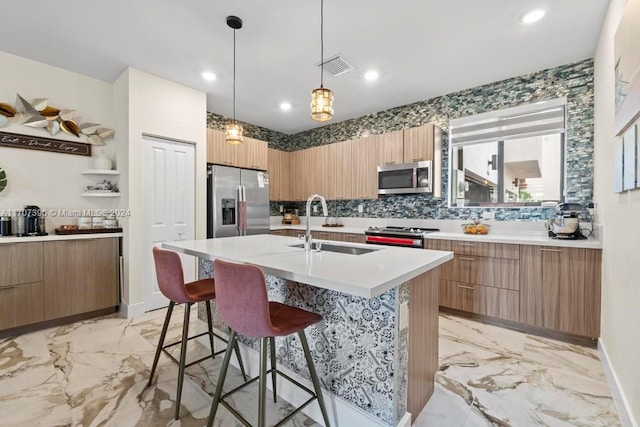 kitchen with a breakfast bar, a kitchen island with sink, sink, decorative backsplash, and stainless steel appliances