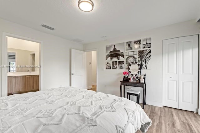 bedroom with connected bathroom, a closet, and wood-type flooring