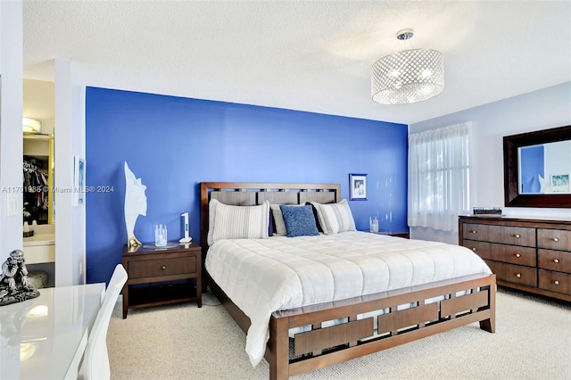 bedroom featuring light colored carpet, a textured ceiling, and connected bathroom