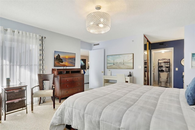 bedroom with a textured ceiling, carpet floors, and ensuite bath