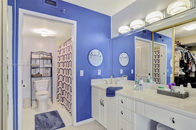 bathroom with vanity, toilet, and a textured ceiling