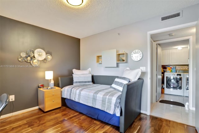 bedroom featuring washer and clothes dryer, dark wood-type flooring, and a textured ceiling