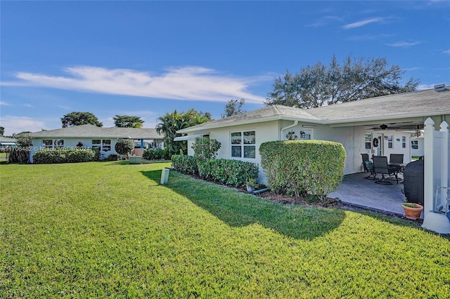 view of side of property with ceiling fan, a patio area, and a lawn