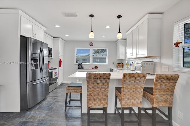 kitchen featuring kitchen peninsula, a kitchen breakfast bar, stainless steel appliances, sink, and white cabinetry