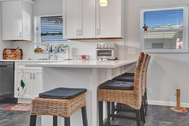 kitchen featuring a breakfast bar, black dishwasher, and white cabinetry