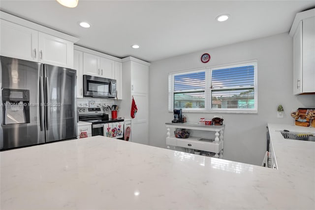 kitchen with light stone countertops, backsplash, stainless steel appliances, sink, and white cabinetry