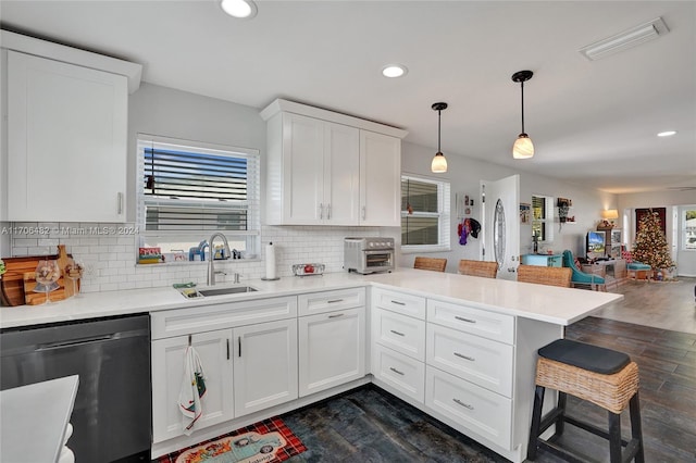 kitchen with stainless steel dishwasher, kitchen peninsula, pendant lighting, a breakfast bar, and white cabinets