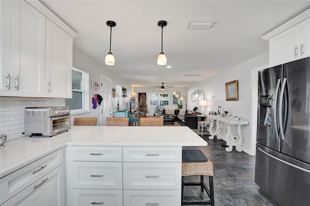 kitchen featuring pendant lighting, ceiling fan, stainless steel fridge, and white cabinetry