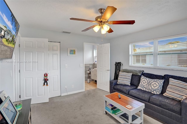 living room featuring ceiling fan, light colored carpet, and a textured ceiling