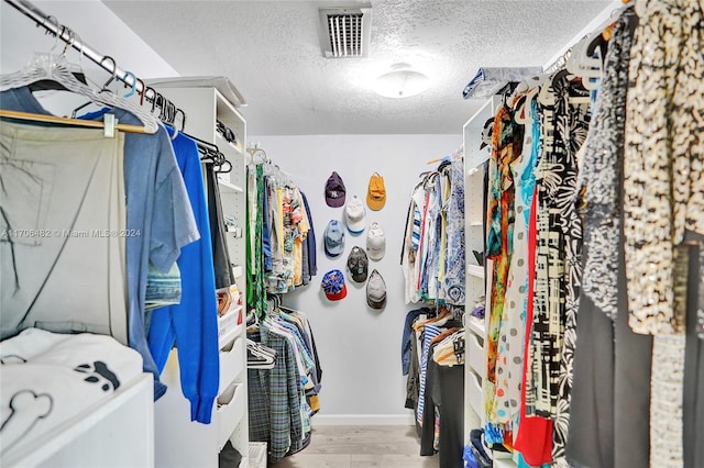 walk in closet with light hardwood / wood-style floors