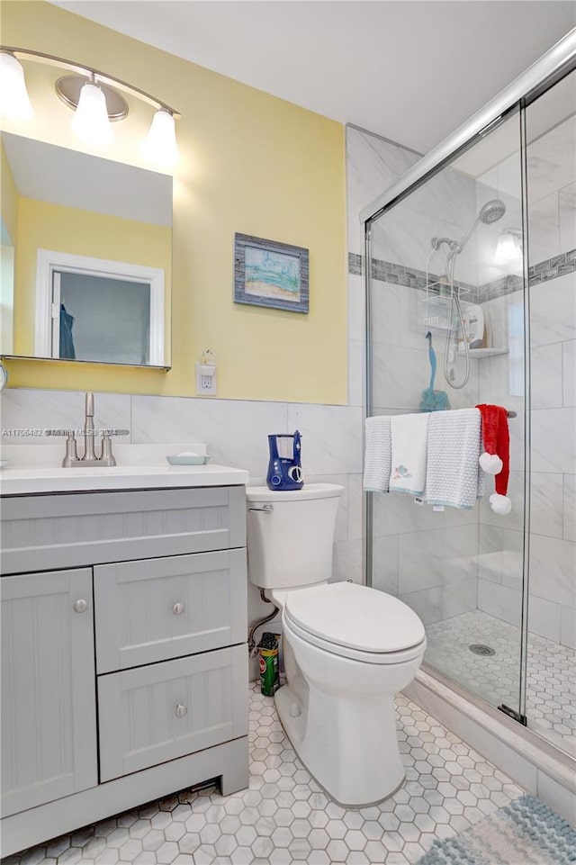 bathroom featuring walk in shower, tile patterned flooring, toilet, vanity, and tile walls